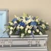 White and blue floral spray arranged on a silver casket