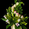 Pale pink roses and white lilies rise above tall green snapdragon-like spikes