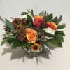 Low arrangement of orange and white roses with yellow mums in a clear glass vase