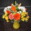 Colorful mixed bouquet in a yellow vase with daisies, roses, and lilies