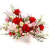 Red and pink rose arrangement in a white square vase