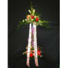 Tall two-tiered standing floral spray with red flowers and printed ribbons on a black background