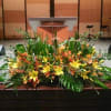 Large yellow and orange floral arrangement with lilies in front of a wooden podium
