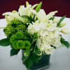 White lilies and hydrangeas with green pompons in a dark vase