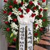 Large standing floral spray with red roses and white lilies, topped with a white bow