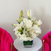 White floral arrangement in a square glass vase on a round table