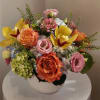 Mixed bouquet of roses, orchids, and hydrangeas in a white vase