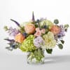 Peach roses and hydrangeas in a clear glass vase with lavender accents