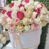 Round hatbox of white, pink, and blush roses tied with a pink ribbon