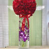 Tall glass vase with submerged purple orchids topped by a large red rose sphere and red ribbon