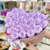 Heart-shaped box filled with tightly packed lavender roses held in both hands