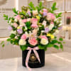 Mixed pink, white, and lavender flowers in a black hatbox with a pink ribbon