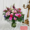Pink and purple mixed bouquet in a glass vase beside a gold candlestick