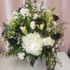 White and black floral arrangement in a white vase with lilies, roses, and hydrangea