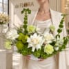 Woman holding a white bowl arrangement of white flowers and green blooms