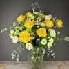 Yellow and white roses in a clear glass vase with airy filler flowers