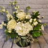 White roses and hydrangeas in a low green vase with mixed greenery