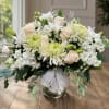 White and pale peach floral arrangement in a glass vase