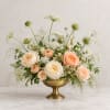 Peach and white roses arranged in a gold pedestal bowl