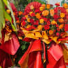 Large bouquet of red, orange, and yellow roses wrapped in red and gold paper