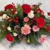 Red and pink carnations with pinecones in a holiday arrangement
