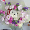 Bouquet of white, pink, and purple flowers in clear wrap with a red ribbon