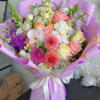 Mixed bouquet of pink, white, and purple flowers wrapped in lavender paper