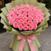 Large bouquet of pink roses wrapped in pale green paper with a pink ribbon