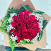 A dense, hand-tied cluster of vivid red roses-framed by delicate white filler