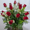 Red roses arranged in a clear glass vase with white filler flowers