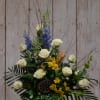 White roses with blue and yellow flowers in a black vase