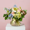 Mixed pastel bouquet in a round glass vase with a striped ribbon