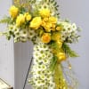 Yellow roses and white daisies arranged in a cross-shaped floral tribute