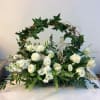 White floral arrangement with a decorative cross and ivy arch