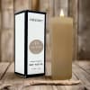 Lit beige soy votive candle beside its box