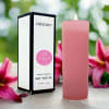 Pink soy votive candle beside its box with stargazer lilies in the background