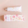 Hand cream tube and floral box on a pale pink background