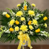 Yellow roses and chrysanthemums in a white vase with a yellow ribbon