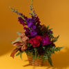 Mixed bouquet in a woven basket with red and purple flowers
