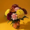 Bouquet of chrysanthemums and carnations in a glass vase with a pink ribbon