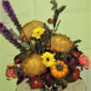 Autumn floral arrangement with yellow blooms and a small pumpkin