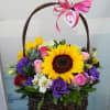 Basket of mixed flowers with a large sunflower and pink ribbon