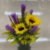 Sunflowers and purple flowers arranged in a square glass vase