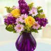 Yellow roses and pink daisies in a purple glass vase