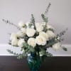 White roses in a blue glass vase with airy eucalyptus stems