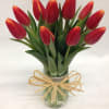 Red tulips in a glass jar tied with a raffia bow