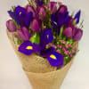 A striking hand-tied bouquet featuring rich purple tulips and vibrant royal-blue irises
