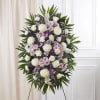 Standing funeral spray with white, pink, and purple flowers on an easel