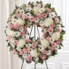 Heart-shaped floral wreath with pink and white flowers on a stand