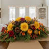 Low fall centerpiece with yellow and red mums, pinecones, berries, and mini pumpkins on a table runner